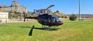 Bell 206 προσγειωμένο σε γρασίδι στα Μετέωρα με φόντο λόφο